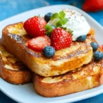 Eggless French toast with golden crust, topped with strawberries, blueberries, and whipped cream