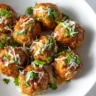 Juicy taco meatballs topped with shredded cheese and fresh cilantro on a white plate