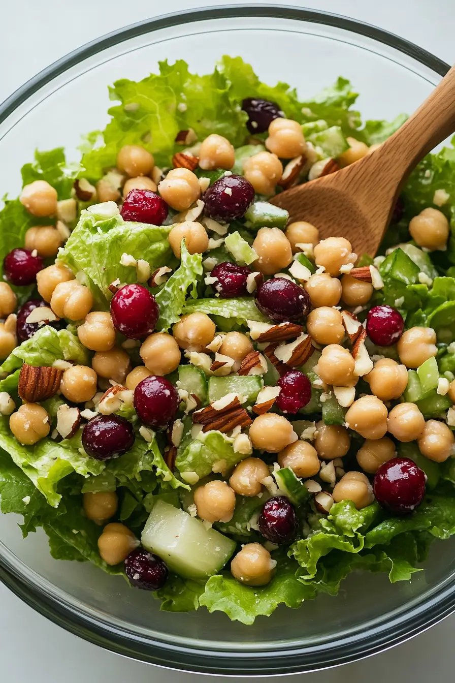 Lettuce cranberry nuts chickpea salad with mixed greens, dried cranberries, pecans, and garbanzo beans in glass bowl