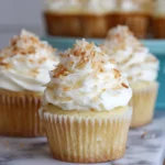 Coconut cream pie cupcake with whipped cream and toasted coconut flakes on top