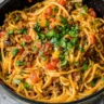Taco spaghetti recipe easy with ground beef, tomatoes, and melted cheese in one skillet