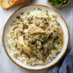 Smothered chicken and rice crock pot meal with creamy shredded chicken, mushrooms, and gravy over white rice, garnished with parsley