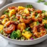 A close-up shot of a healthy Caribbean shrimp bowl in a white bowl, filled with seasoned shrimp, pineapple chunks, and broccoli florets over couscous.