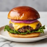 Lipton french onion soup burgers with cheddar cheese, lettuce, and red onion on a brioche bun