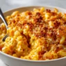 A close-up shot of a bowl of creamy butternut squash mac and cheese, topped with golden-brown toasted breadcrumbs, with a fork digging in to show the cheesy texture.