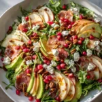 Autumn harvest salad with apple, feta, arugula, avocado, pomegranate, candied pecans, and vinaigrette