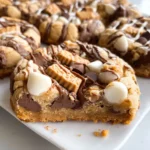 Cookie bars overloaded with chocolate chips, peanut butter candies, and white chocolate drizzle.
