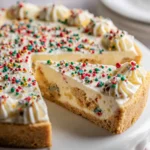 Rich sugar cookie cheesecake topped with whipped cream and colorful Christmas sprinkles.