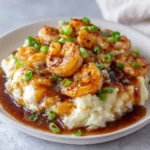 Creamy mashed potatoes topped with savory gravy, sautéed shrimp, and fresh scallions