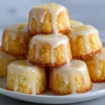 Mini lemon cakes with tangy glaze and lemon zest.