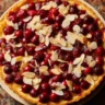 Cranberry tart topped with sliced almonds on a crisp buttery crust, perfect for holiday baking