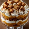 Layers of pumpkin puree, butterscotch, gingerbread cubes, and whipped cream in a glass trifle bowl
