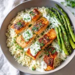 Seared salmon over rice, drizzled with creamy herb sauce and served with roasted asparagus