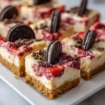 Creamy cheesecake bars with strawberry swirl, golden crust, and Oreo cookie garnish.
