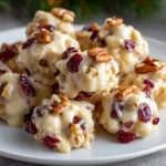 Clusters of white chocolate with dried cranberries and pecans on a plate.
