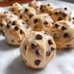 Frozen Greek Yogurt Peanut Butter Bites, featuring creamy spheres studded with chocolate chips, arranged on a white plate with a slightly chilled and smooth texture.