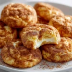 Snickerdoodle cheesecake cookies with creamy filling and cinnamon topping.