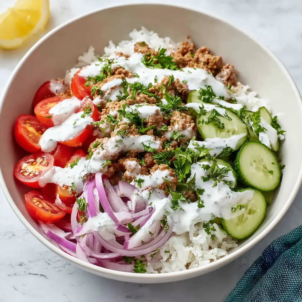 Fresh Mediterranean turkey bowl with seasoned ground turkey over white rice, sliced cucumbers, cherry tomatoes, red onions, tzatziki sauce, and fresh parsley