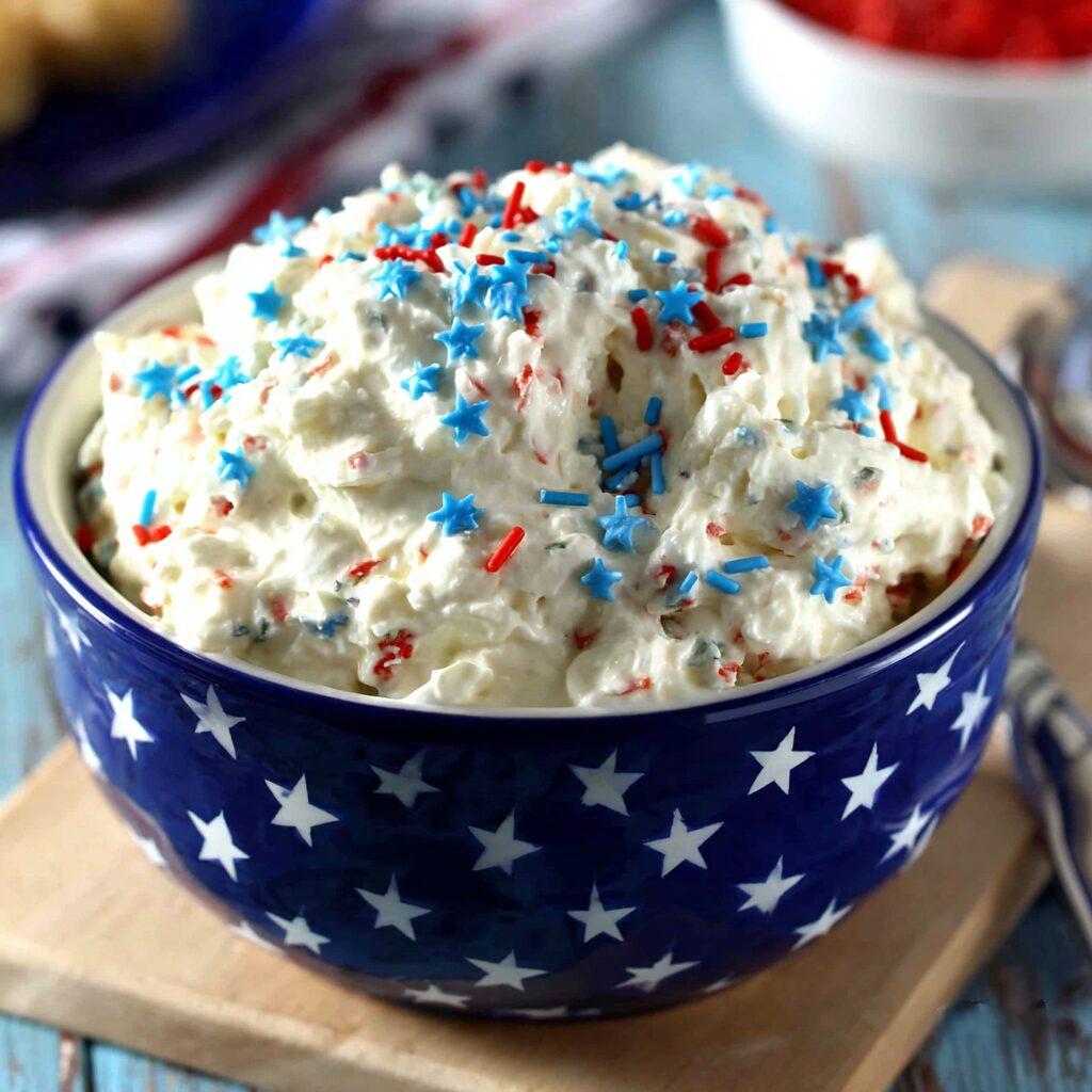 Red, white, and blue sprinkles transform creamy cake batter dip into a festive treat, perfect for dipping cookies or fruit.