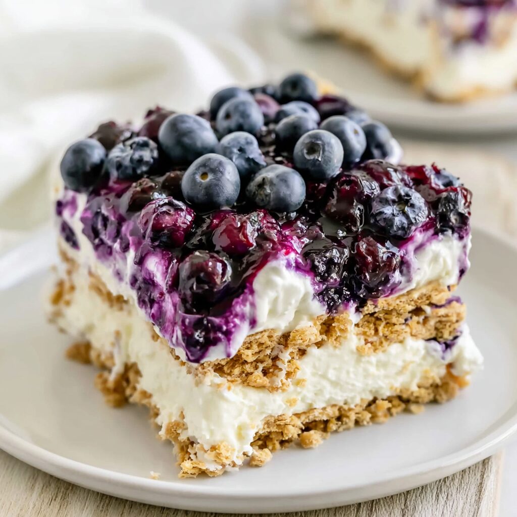 A refreshing no-bake dessert featuring layers of whipped cream, graham crackers, and a swirl of blueberry compote.