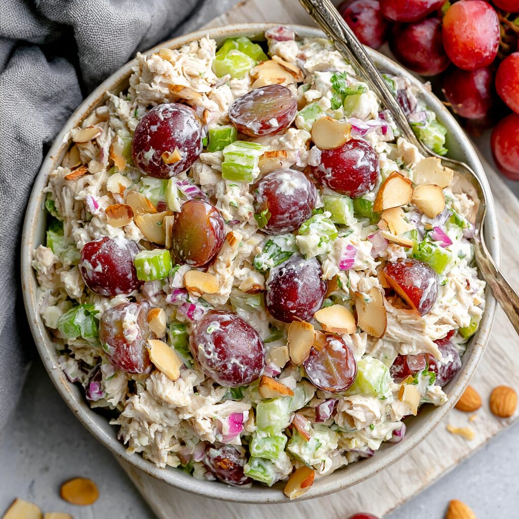 A serving of creamy chicken salad studded with halved green grapes and slivered almonds.