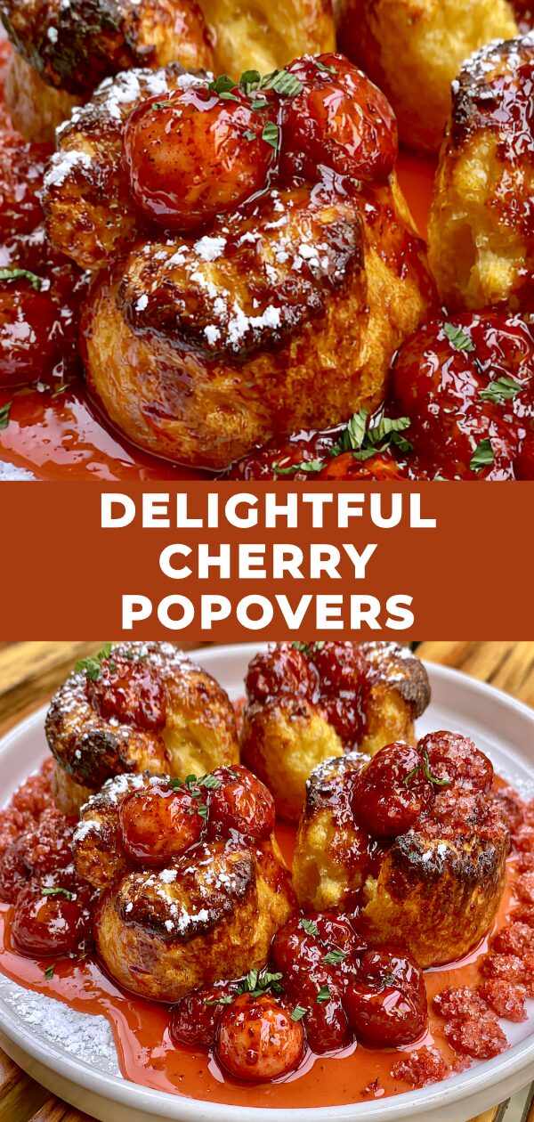 Fluffy, golden-brown popovers are topped with glistening red cherries and a dusting of powdered sugar.